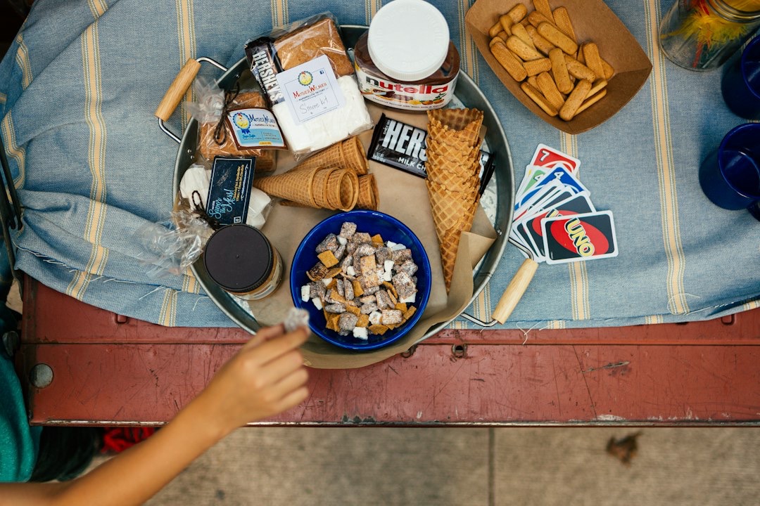 A hand reaches for snacks from a bowl on a picnic tray.